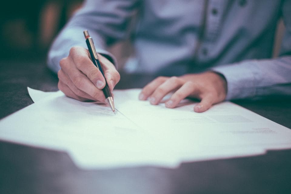 Hands signing a paper agreement at a desk